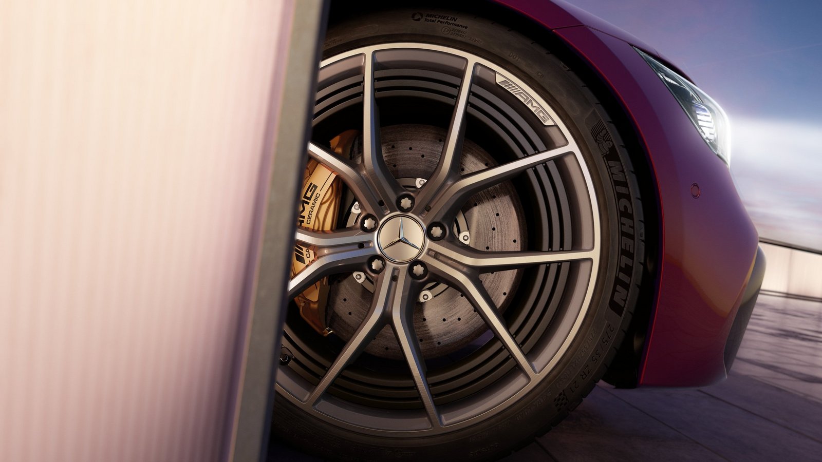 Nahaufnahme der AMG Felge eines Mercedes-AMG Modells, das die edle Alufelge mit markanten Linien und die goldfarbenen Bremssättel zeigt, unterstrichen durch die Michelin Hochleistungsreifen.