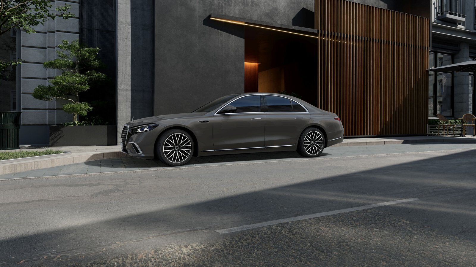 Seitliche Ansicht einer geparkten Mercedes-Benz S-Klasse Limousine vor einem modernen Gebäude mit dunkler Fassade und vertikalen Holzlamellen