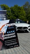 Flyer mit Informationen zum Automarkt Ergolding am 26. April 2026 vor einem weißen Mercedes-Benz auf gepflastertem Platz mit Bäumen im Hintergrund