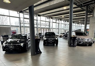 Innenraum eines Autohauses mit mehreren geparkten Autos auf hellen Fliesen und großen Fenstern im Hintergrund