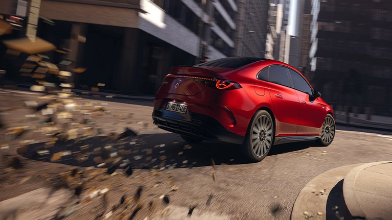 Mercedes-Benz CLA 250+ in Rot fährt durch die Stadt, aufgenommen in sportlicher Rückansicht mit dynamischer Bewegungsunschärfe.