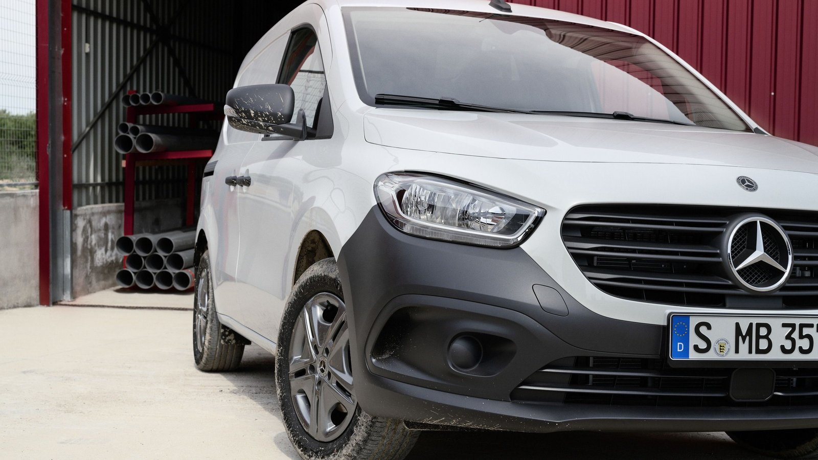 Mercedes-Benz Citan Kastenwagen in Weiß, Frontansicht auf einer Baustelle mit Metallrohren im Hintergrund.