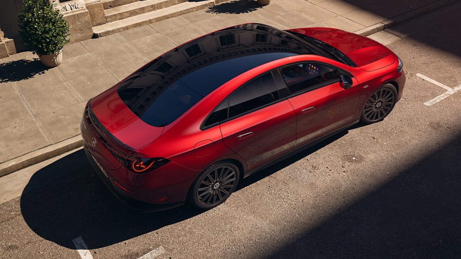 Mercedes-Benz CLA 250+ in Rot aus schräger Vogelperspektive – markantes Coupé-Design mit durchgehendem Panoramaglasdach.