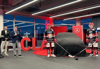 4 Personen, darunter 2 Eishockey-Spieler des EVL vor einem verhüllten Mercedes-Benz PKW