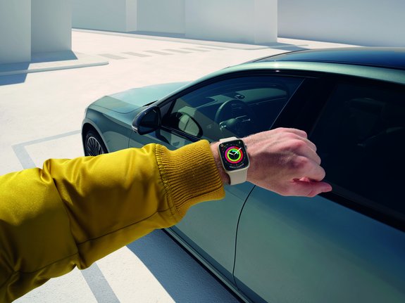 Hand mit Apple Watch vor Mercedes-Benz, Verbindung zu Fahrzeugfunktionen über die Smartwatch.