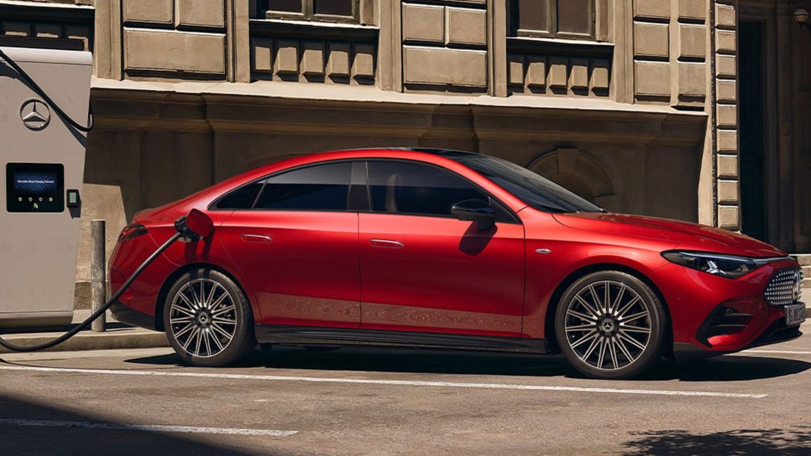 Roter Mercedes-Benz CLA 250+ an öffentlicher Ladestation in urbaner Umgebung – modernes Design trifft Elektromobilität.